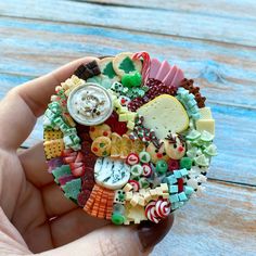 a hand holding a small brooch with many different types of buttons and candy on it