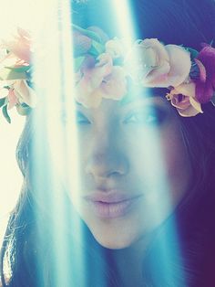 a woman with flowers in her hair looking out the window