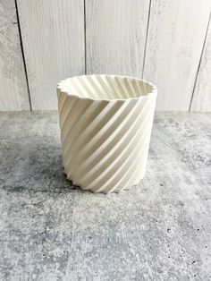 a white vase sitting on top of a wooden table