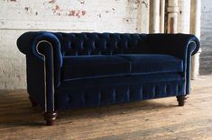 a blue velvet chesterfield sofa in an old brick room with wooden floors and exposed ceilings