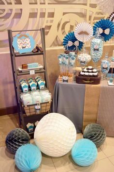 the dessert table is set up with blue and white decorations, paper fans, and cupcakes