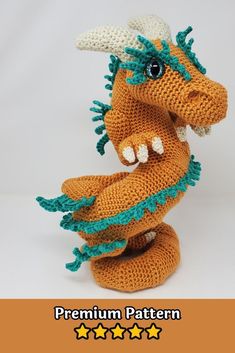 a crocheted dragon stuffed animal sitting on top of a white surface with stars around it