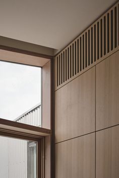 an open window in a room with wooden paneling on the walls and below it is a bench