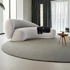 a modern living room with black and white curtains, round rugs and an upholstered couch