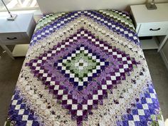 a bed with a purple and green quilt on it