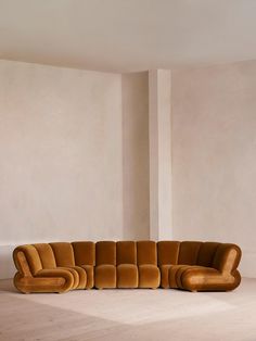 a large brown couch sitting on top of a white floor next to a tall wall