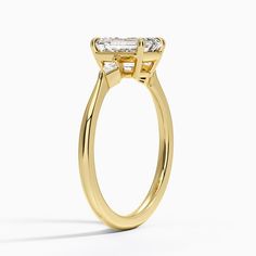 a yellow gold engagement ring with an oval cut diamond in the center and side stones