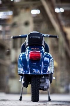 the back end of a blue motorcycle parked in a garage