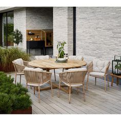 an outdoor table and chairs on a wooden deck with potted plants in the background