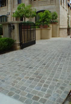 an iron gate is on the side of a brick walkway in front of a building