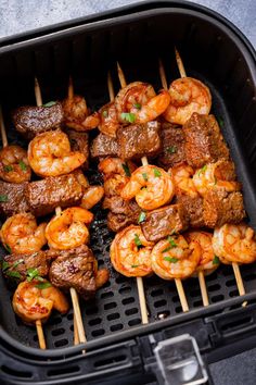 meat and shrimp skewers in an air fryer with toothpicks on the side