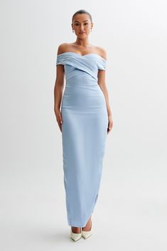 a woman in a light blue dress with one shoulder draped over her shoulders and white shoes