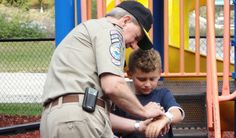 a police officer helping a young boy play on the playground