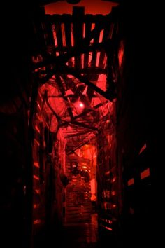 a dark hallway with red light coming from the ceiling