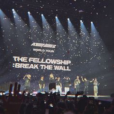 a group of people standing on top of a stage with their hands in the air