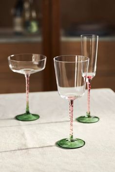 three empty wine glasses sitting on top of a white tablecloth covered table with pink trimmings