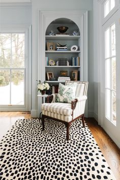 a chair sitting on top of a rug in front of a book shelf filled with books