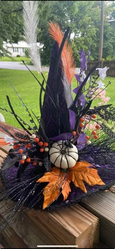 a purple hat with feathers and pumpkins is sitting on a bench