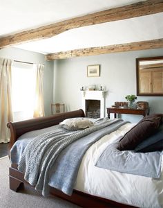 a bed sitting next to a window in a bedroom under a painting on the wall