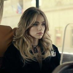 a woman sitting on a bus looking off into the distance