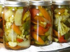 four jars filled with different types of vegetables