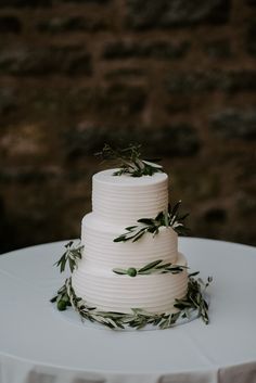 a white wedding cake with greenery on top