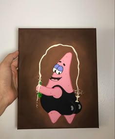 a hand holding up a painting of a cartoon character