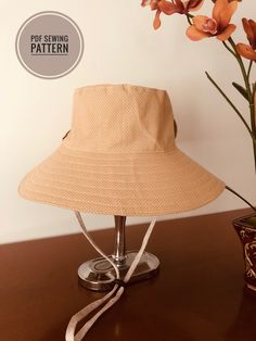 a tan hat sitting on top of a wooden table next to a vase with flowers