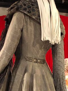 a woman's dress on display in front of a red curtain