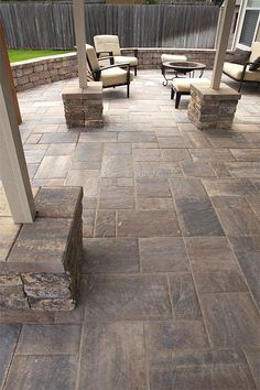 an outdoor patio with chairs and fire pit in the back yard, surrounded by stone pavers