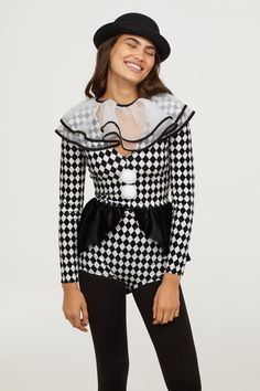 a woman wearing a black and white checkered top with sheer neckline, leggings and heels