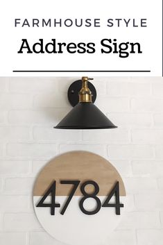 the farmhouse style address sign is mounted on a white brick wall with a black lamp