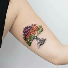 a woman's arm with a colorful tree tattoo on it