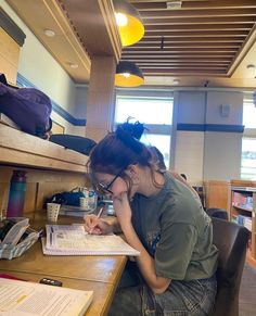 a woman sitting at a desk writing in a book