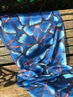 This beautiful, hand painted silk scarf is a wearable piece of art. Butterflies, in shade of blue with an orange accent, and outlined in black, have been hand painted onto the silk with specialist silk paint. The outline of the design is first drawn and then the colours are applied with brushes - the whole process takes many very enjoyable hours. The scarf has been professionally streamed in order to permanently fix the colours and preserve their vibrancy. This steaming process leaves the silk p Artistic Blue Silk Scarf For Spring, Hand Painted Blue Silk Scarf For Summer, Blue Hand Painted Silk Scarf, Artistic Handmade Blue Silk Scarf, Blue Bohemian Hand Painted Silk Scarf, Blue Hand Painted Bohemian Silk Scarf, Bohemian Blue Hand Painted Silk Scarf, Artistic Blue Silk Scarves, Artistic Blue Silk Scarf