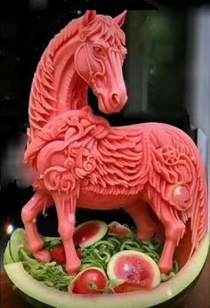 a pink horse statue sitting on top of a watermelon slice