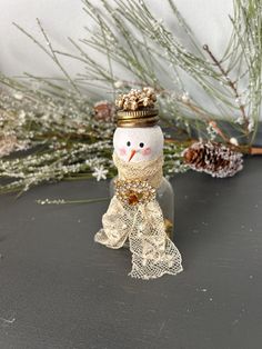 a snowman with a crown on it's head sitting next to pine cones