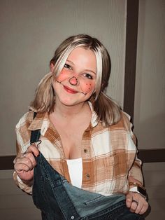 a woman with makeup on her face and nose is holding an old pair of jeans