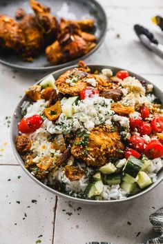 two bowls filled with rice, meat and veggies on top of a table