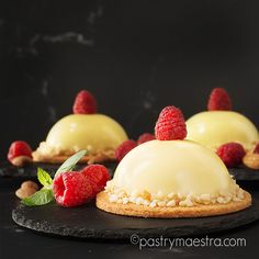 three desserts with raspberries and almonds on black slate platter for serving