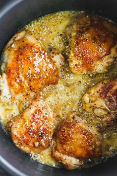 some chicken is cooking in a pot with broth and seasoning on it's side