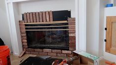 a brick fireplace is being built in the corner of a room with construction tools on the floor