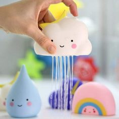 a person holding a toy rain with clouds and rainbows in the background, while other toys are on the table