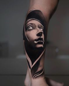 a woman's leg with a black and white tattoo on it, showing her face