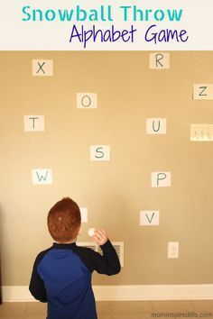 a young boy standing in front of a wall with alphabets on it and the words snowball throw