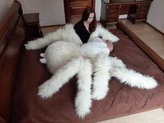 a woman laying on top of a bed covered in giant white furry animal legs and legs