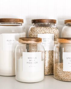 several glass jars with labels on them sitting on a counter