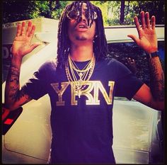 a man with dreadlocks standing in front of a car wearing a t - shirt that says y r n