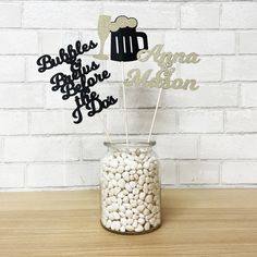 a glass jar filled with white rocks sitting on top of a wooden table next to a brick wall