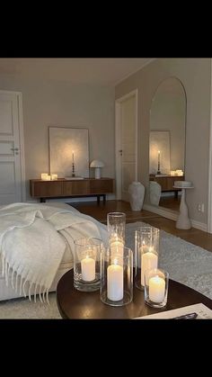 candles sit on a coffee table in the middle of a living room with white furniture